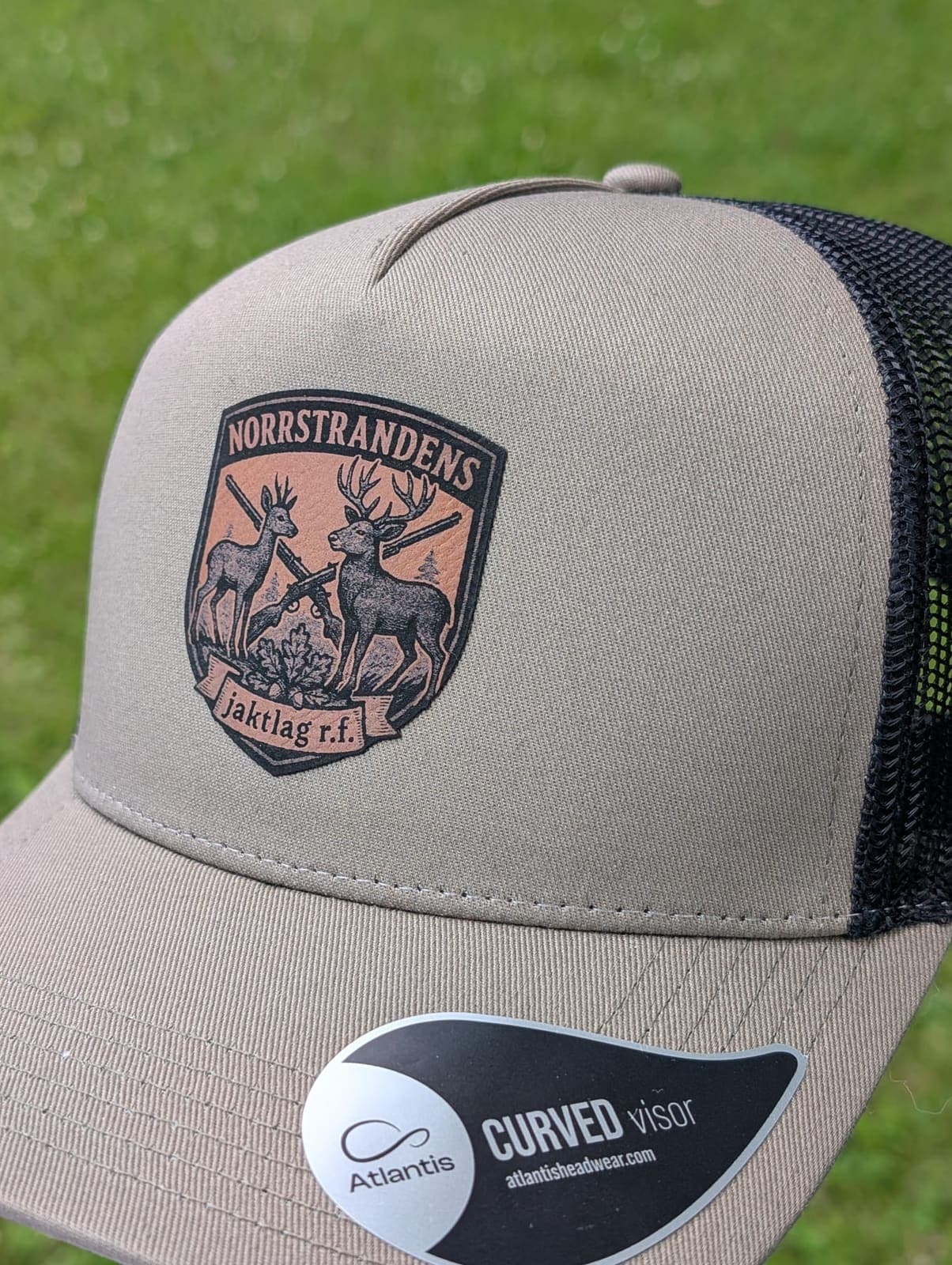 Grå keps med Norrstrandens jaktlags emblem i flerfärgstryck