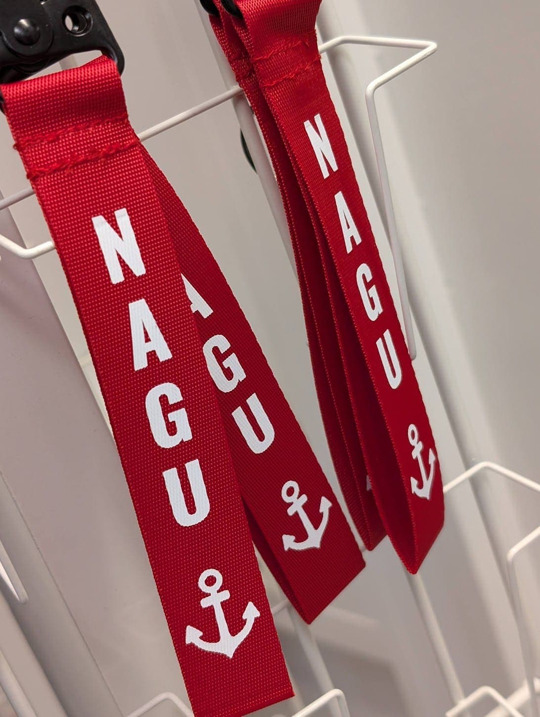 Röda nyckelband med vit Nagu-text och ankarsymbol